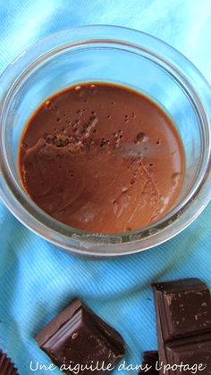 a glass bowl filled with chocolate next to some pieces of chocolate on a blue towel