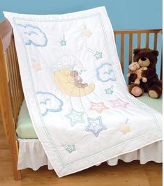 a teddy bear sitting next to a baby crib with a white blanket on it