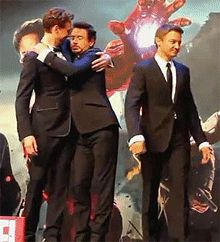 three men in suits hugging each other at a press conference for the movie iron man