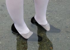 a person wearing white socks and black shoes standing in shallow water