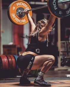 a woman squats while holding a barbell