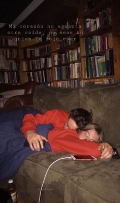 a woman laying on top of a couch next to a book shelf