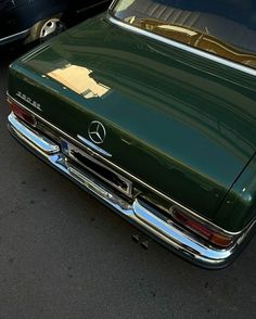 a green car parked next to another black car