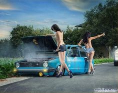 two women are sitting on the hood of a blue car and one is pointing at something