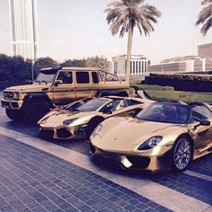 three gold sports cars parked next to each other in front of palm trees and buildings