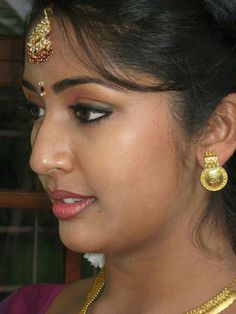 a woman wearing a gold necklace and matching earring with a pair of earrings on her head