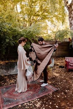 a man and woman standing on top of a rug covered in a brown shawl