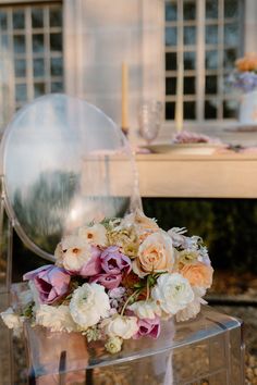 a bouquet of flowers sitting on top of a clear chair in front of a table