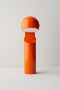 an orange object with a white light on it's top is standing upright in front of a wall