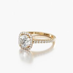 a yellow gold engagement ring with an oval diamond center and pave set diamonds around the band