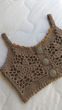 a crocheted top is laying on the bed