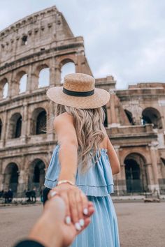 a woman holding the hand of a man in front of an old building