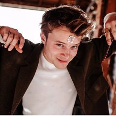 a young man is holding onto his hair and looking at the camera while wearing a pair of scissors