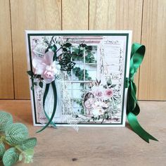 a card with flowers and ribbons on the front, sitting next to a green ribbon