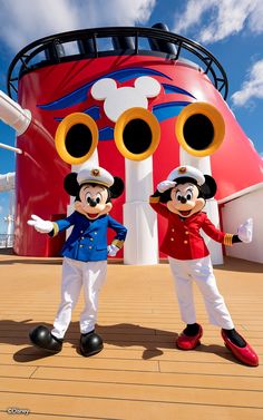 two mickey mouse characters standing in front of a large ship