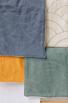 four different colors of linens on top of each other, with stitching in the middle