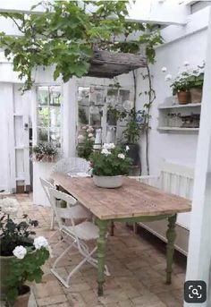 an outdoor dining area with potted plants on the table and benches in the background