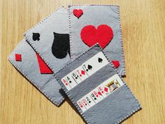 two pieces of felt with playing cards on them sitting on a wooden table next to each other