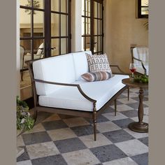 a white couch sitting on top of a checkered floor next to a glass door