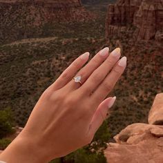a woman's hand with a diamond ring on top of her finger in the desert