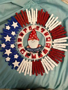 a patriotic wreath made out of popsicle sticks with a gnome in the center and welcome america written on it