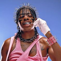 a woman with piercings on her face and wearing a pink tank top is holding a toothbrush to her mouth