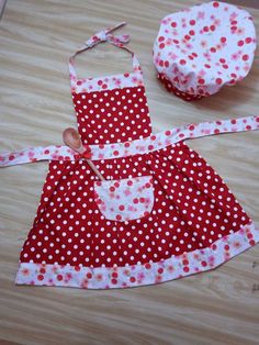 a red and white polka dot apron with wooden spoon next to it on a table