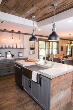 a large kitchen with an island and two pendant lights hanging from it's ceiling