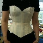 a woman wearing a white corset and black pants
