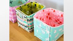 four colorful storage baskets sitting on top of a wooden floor