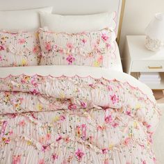 a bed with pink and yellow flowers on the comforter, pillows and pillow cases