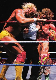 two men wrestling in a ring with one holding the other's arm around his neck