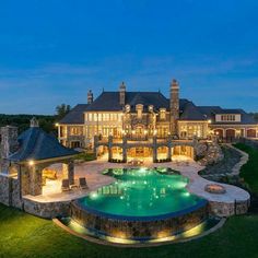 an aerial view of a large mansion with a pool in the foreground at night