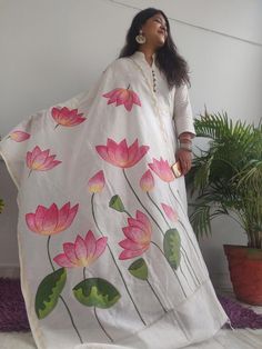 a woman standing in front of a potted plant wearing a white blanket with pink flowers on it