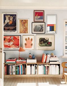 a room with many pictures on the wall and bookshelves in front of it