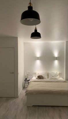 a white bed sitting under two black lights in a bedroom next to a doorway and closet