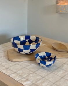 two blue and white bowls sitting on top of a cutting board next to wooden spoons