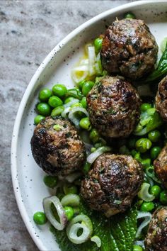 a white plate topped with meatballs and peas