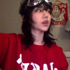 a woman wearing goggles and a red shirt with white letters on it is taking a selfie