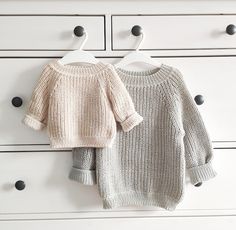 two sweaters hanging on the wall next to each other in front of white drawers