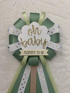 a green and gold ribbon with the words mommy to be on it