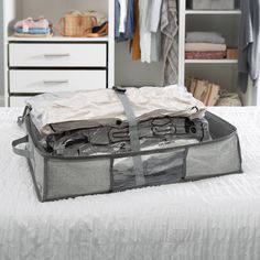 an open suitcase sitting on top of a bed next to a white dresser and drawers