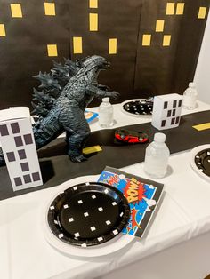 a table topped with plates and plastic godzilla toys