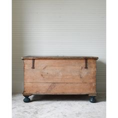 an old wooden chest sitting on wheels in front of a white wall