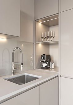 a kitchen with white cupboards and a stainless steel sink in front of a coffee maker