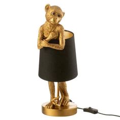 a gold monkey lamp with a black shade on it's head and arms crossed