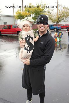 a man holding a child in his arms while wearing a hat and black sweatpants