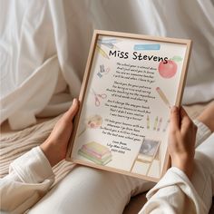 a person sitting on the floor holding up a framed poster that reads, miss stevens