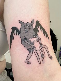 a woman with a tattoo on her leg holding onto a small creature in the shape of a bat