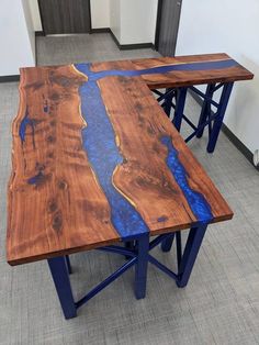 two tables made out of wood with blue paint on the top and one has a river running through it